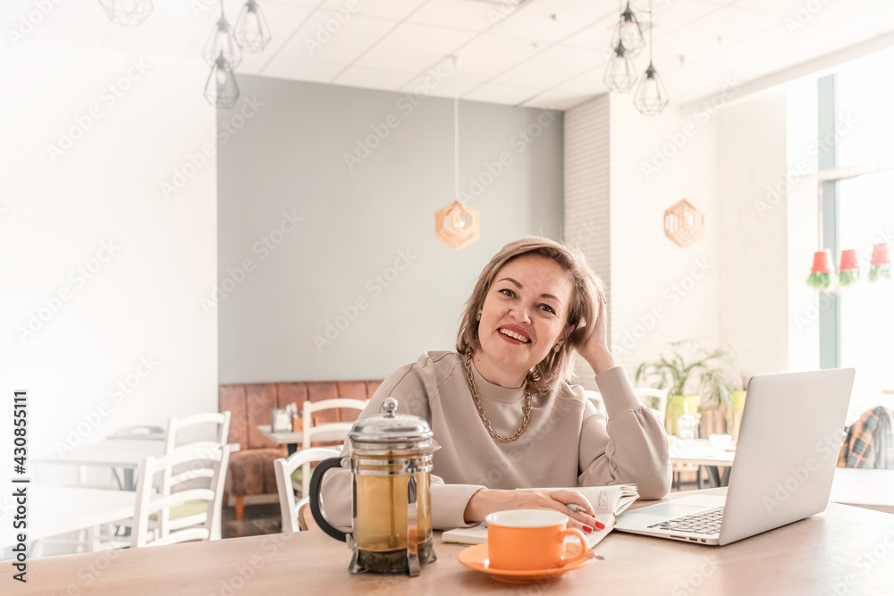 An adult female psychologist coach conducts an online consultation in the bright interior of a cafe with a laptop and a phone on the table. the concept of remote work and psychological assistance. An adult female psychologist coach conducts an online consultation in the bright interior of a cafe with a laptop and a phone on the table. the concept of remote work and psychological assistance.