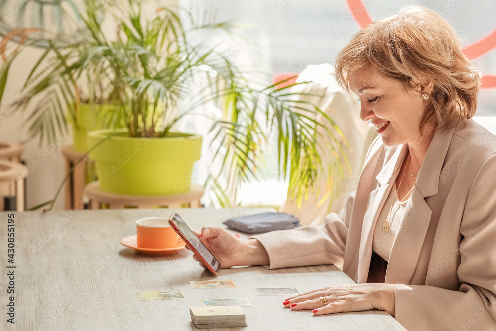a female psychologist-trainer conducts an online consultation using Symbolon cards in the interior of a cafe. the concept of remote work and psychological assistance