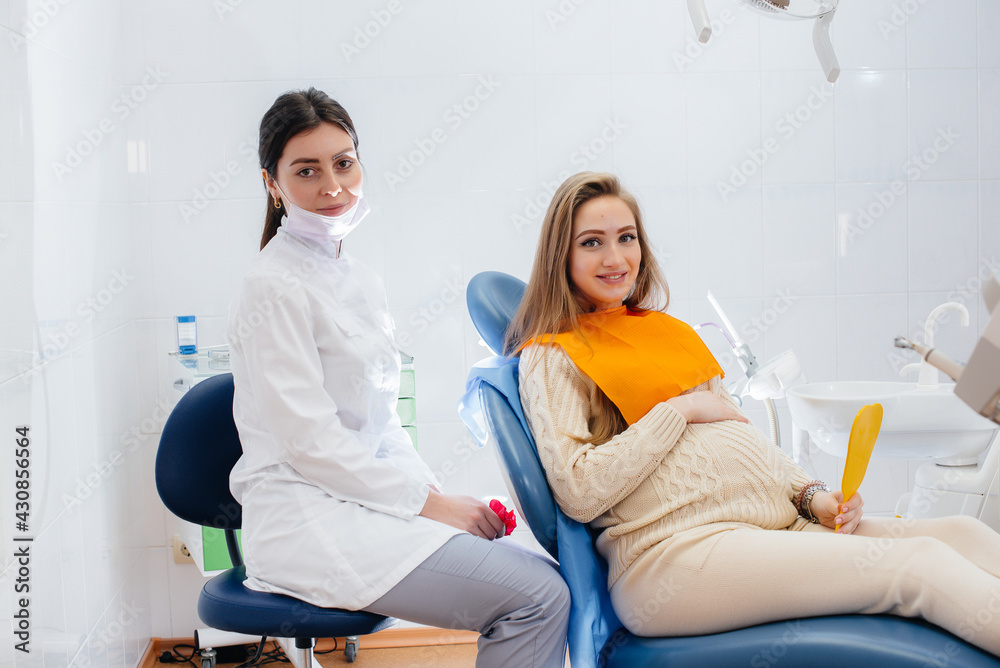 Obraz premium A professional dentist treats and examines the oral cavity of a pregnant girl in a modern dental office. Dentistry