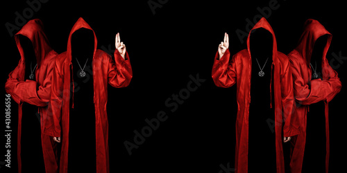 People dressed in a red robes looking like a cult members on a dark background. Pointing up with fingers. Ghostly figure. Sectarian. Copy space.  photo