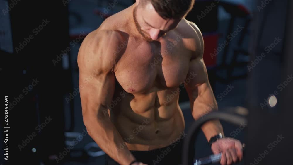 Training muscles. Sportsman pumping his trained body on a simulator. Strong trainer doing workout. Exercise to improve strength at fitness club. Close-up. Training muscles. Sportsman pumping his trained body on a simulator. Strong trainer doing workout. Exercise to improve strength at fitness club. Close-up.