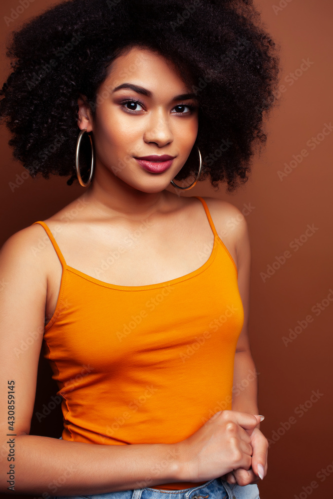 Fototapeta premium pretty young african american woman with curly hair posing cheerful gesturing on brown background, lifestyle people concept