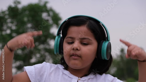 UDAIPUR, INDIA - APRIL 29, 2021: Girl kid with headphones listening music