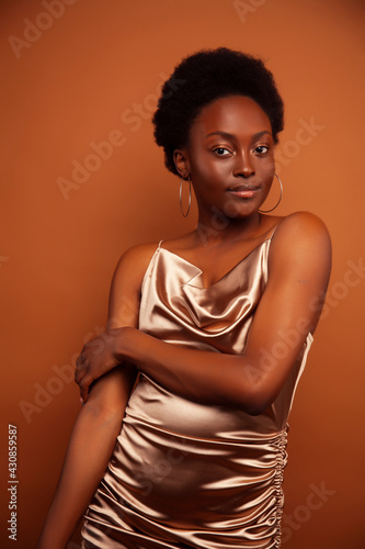 pretty young african american woman with curly hair posing cheerful gesturing on brown background, lifestyle people concept © iordani