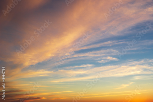 Dramatic majestic clouds on blue sky with yellow pink tones in sunset light  beautiful scenic cloudscape in sundown dusk