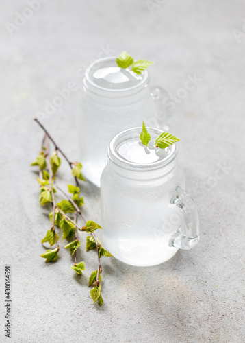 Russian drink, natural fresh birch juice in a glass jar on a light gray background