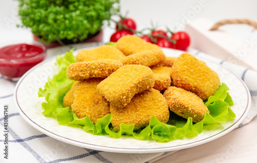 Chicken nuggets on a plate with lettuce leaves. Served on a napkin.