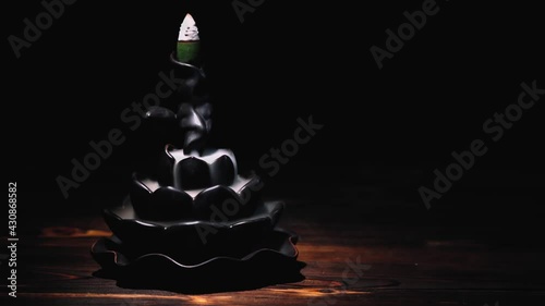 Incense cones holder. Ceramic backflow incense burner in the form of lotus flower. Dark mystic concept.