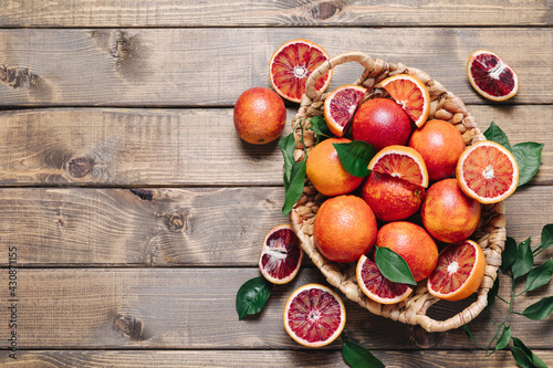Pile of blood oranges in a basket on a wooden table background. Flat lay, top view, copy space