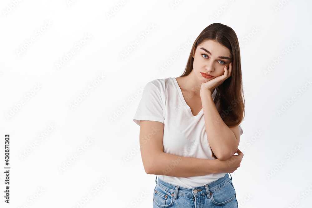 Gloomy bored girl student lean face on hand and look indifferent at camera, listening boring person, stare with blank reluctant expression, standing over white background Gloomy bored girl student lean face on hand and look indifferent at camera, listening boring person, stare with blank reluctant expression, standing over white background