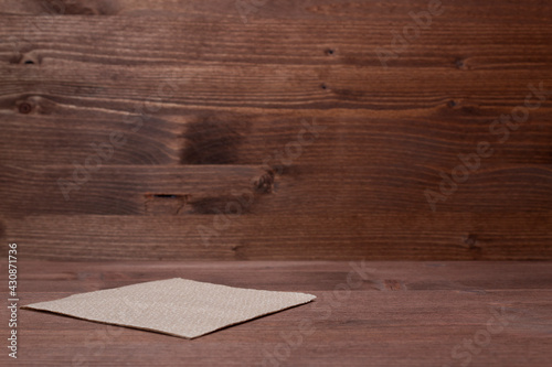Isolated brown paper napkin on wooden background.