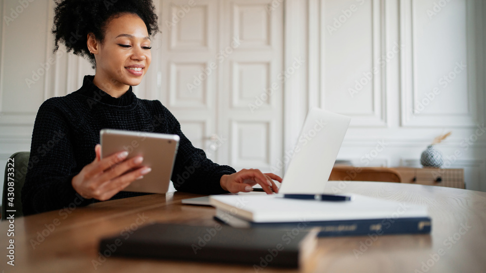 Records costs in a convenient app. A woman keeps online accounting of expenses for a month at home. A contented woman of Afro appearance. Records costs in a convenient app. A woman keeps online accounting of expenses for a month at home. A contented woman of Afro appearance.