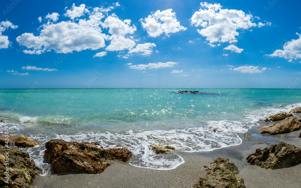 Small waves breaking amoung rocks on the shore of the Gilf of Mexico at Caspersen Beach with blue sky and white clouds in Venice Florida USA Small waves breaking amoung rocks on the shore of the Gilf of Mexico at Caspersen Beach with blue sky and white clouds in Venice Florida USA