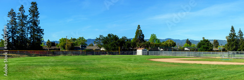Canvas-taulu Panoramic view of an empty softball, baseball field, trees and green grass in ty