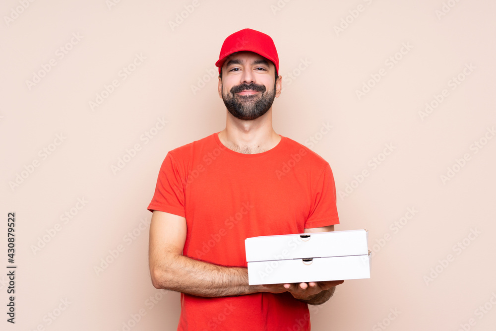Young man holding a pizza over isolated background keeping the arms crossed in frontal position Young man holding a pizza over isolated background keeping the arms crossed in frontal position