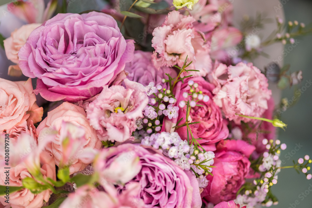 A lush bouquet of light pink, purple, orange cute delicate roses of different sizes, green white small flowers. Close-up.