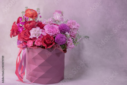 Fototapeta Naklejka Na Ścianę i Meble -  A lush bouquet of red, purple, light pink, white cute delicate small roses of different sizes, flowers in round paper box with geometric pattern. Romance.