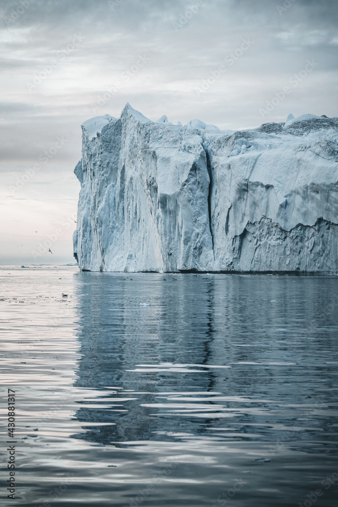 Arctic nature landscape with icebergs in Greenland icefjord with midnight sun sunset sunrise in the horizon. Early morning summer alpenglow during midnight season. Ilulissat, West Greenland. Arctic nature landscape with icebergs in Greenland icefjord with midnight sun sunset sunrise in the horizon. Early morning summer alpenglow during midnight season. Ilulissat, West Greenland.