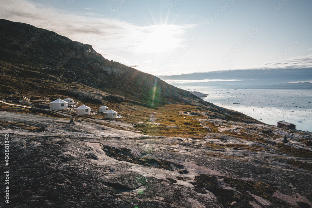 Panoramic image of Camp Eqi at Eqip Sermia Glacier in Greenland. nature landscape with lodge cabins. Midnight sun and pink sky. Tourist destination Eqi glacier in West Greenland AKA Ilulissat and
