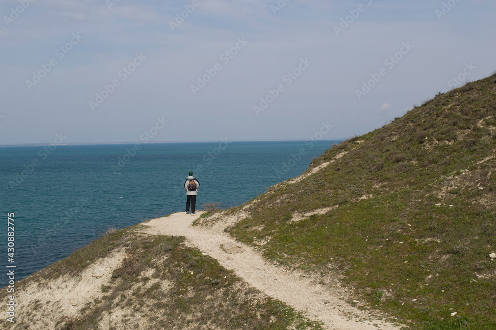 View of the blue sea from the mountainside. A young man looks at the sea. 