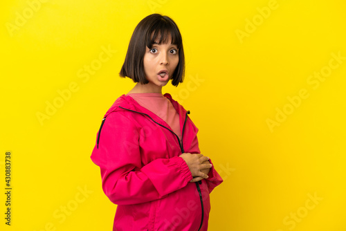 Young pregnant woman over isolated yellow background with surprise facial expression © luismolinero