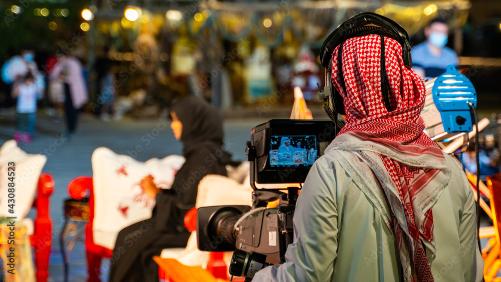 An Arab man recording a live interview video at an outdoor event in Qatar. Selective focus