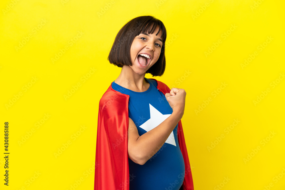 Super Hero pregnant woman isolated on yellow background celebrating a victory Super Hero pregnant woman isolated on yellow background celebrating a victory