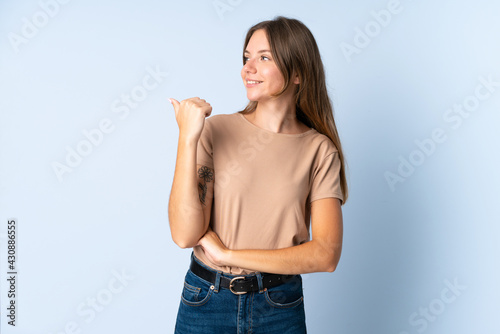 Young Lithuanian woman isolated on blue background pointing to the side to present a product