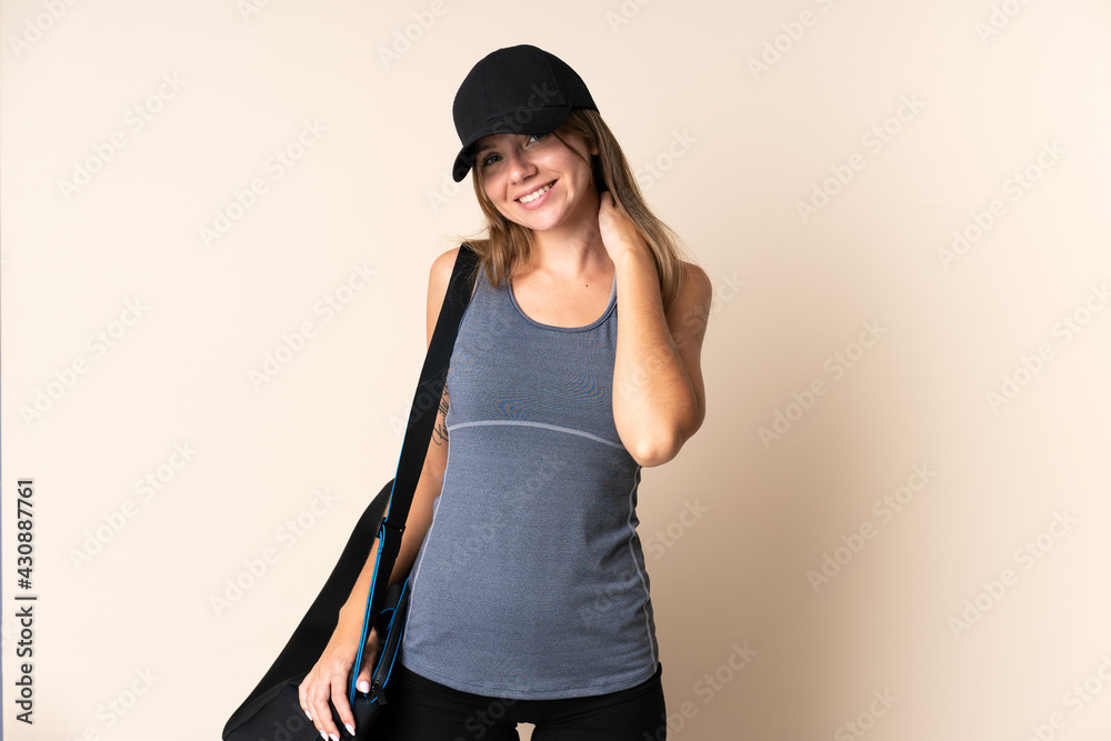 Young sport Lithuanian woman holding a sport bag isolated on beige background laughing Young sport Lithuanian woman holding a sport bag isolated on beige background laughing