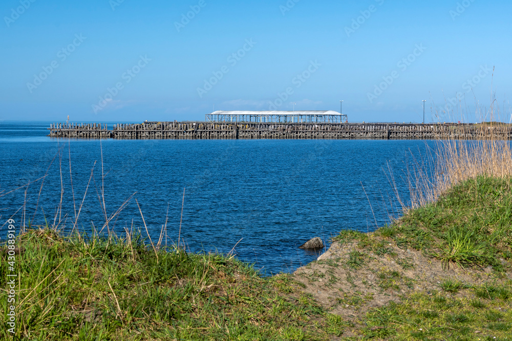 Old abandoned pier seen from grassy shore Old abandoned pier seen from grassy shore