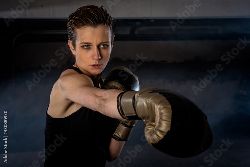 Closeup picture of beautiful female boxer practicing her punches with gold boxing gloves © qunica.com