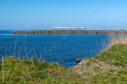 Old abandoned pier seen from grassy shore