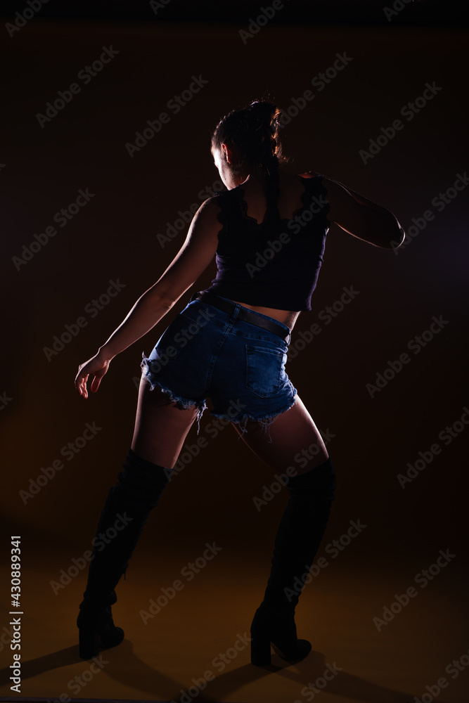 High-contrast silhouette picture of a sexy female model posing on a dark background