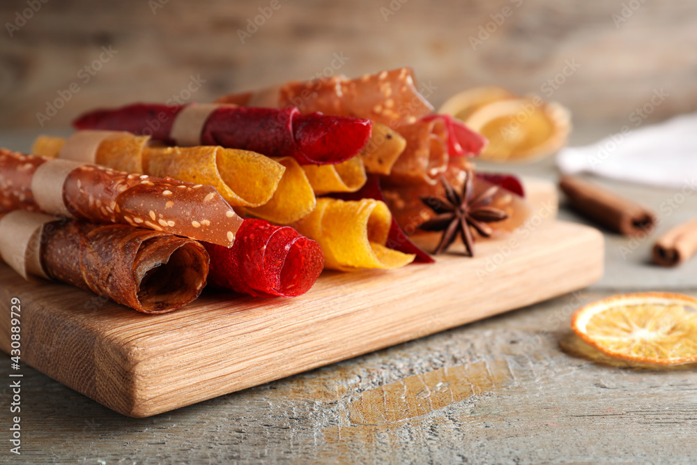 Delicious fruit leather rolls on wooden table, closeup