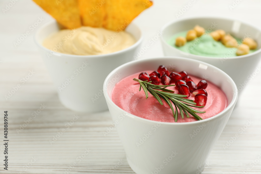 Different kinds of tasty hummus on white wooden table, closeup. Space for text Different kinds of tasty hummus on white wooden table, closeup. Space for text