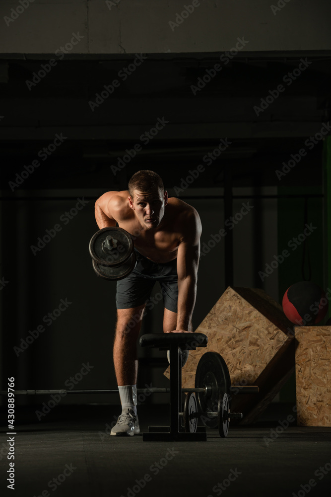 Sportsman doing exercises with weights over fitness bench and looking straight at the camera. Sportsman doing exercises with weights over fitness bench and looking straight at the camera.