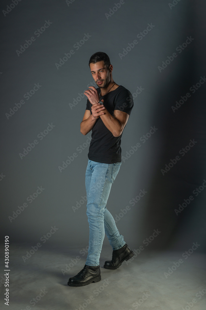 Fototapeta premium Studio photoshoot of a good-looking man posing in jeans and black shirt