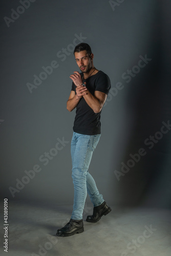Studio photoshoot of a good-looking man posing in jeans and black shirt