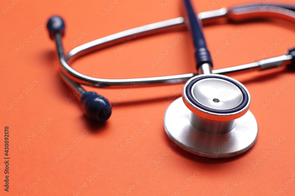 Blue medical stethoscope on orange background. Close up