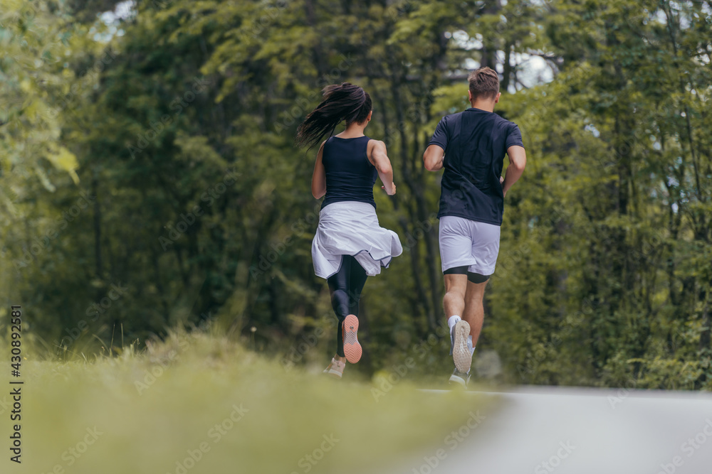 Young fit couple atheltes running on running road in a forest. Young fit couple atheltes running on running road in a forest.