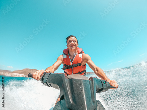 Fényképezés Teenager man enjoying summer in a jet ski in the middle of the sea having fun racing alone and isolated