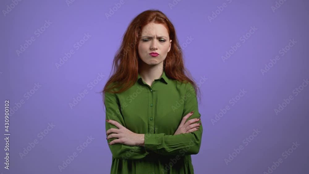 Offended woman keeping arms crossed, feeling mad at someone on violet studio background. Human facial expressions, emotions and feelings. Body language. Offended woman keeping arms crossed, feeling mad at someone on violet studio background. Human facial expressions, emotions and feelings. Body language.