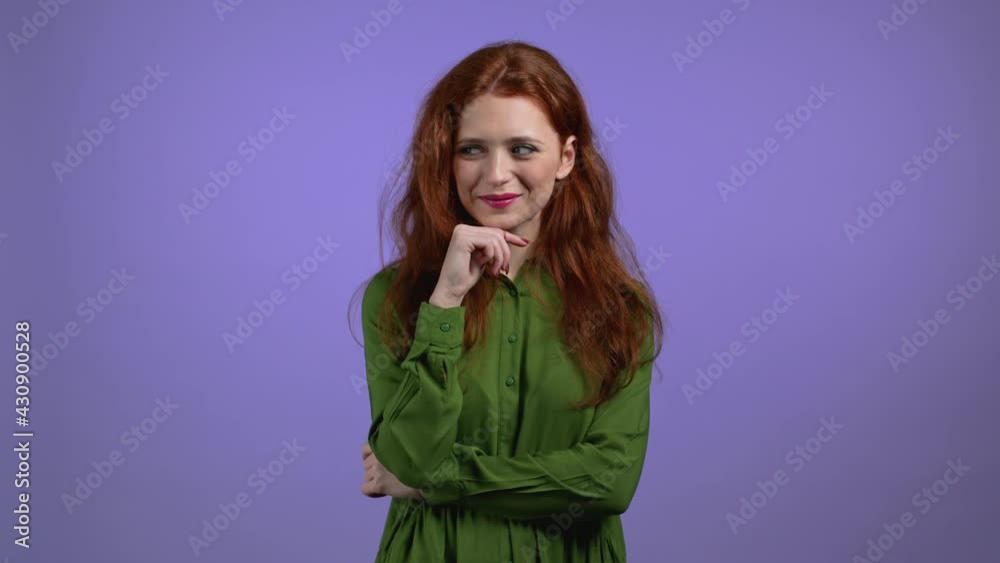 Young woman with long red hairstyle looking to camera, flirting. Beautiful model girl on violet studio background. Young woman with long red hairstyle looking to camera, flirting. Beautiful model girl on violet studio background.