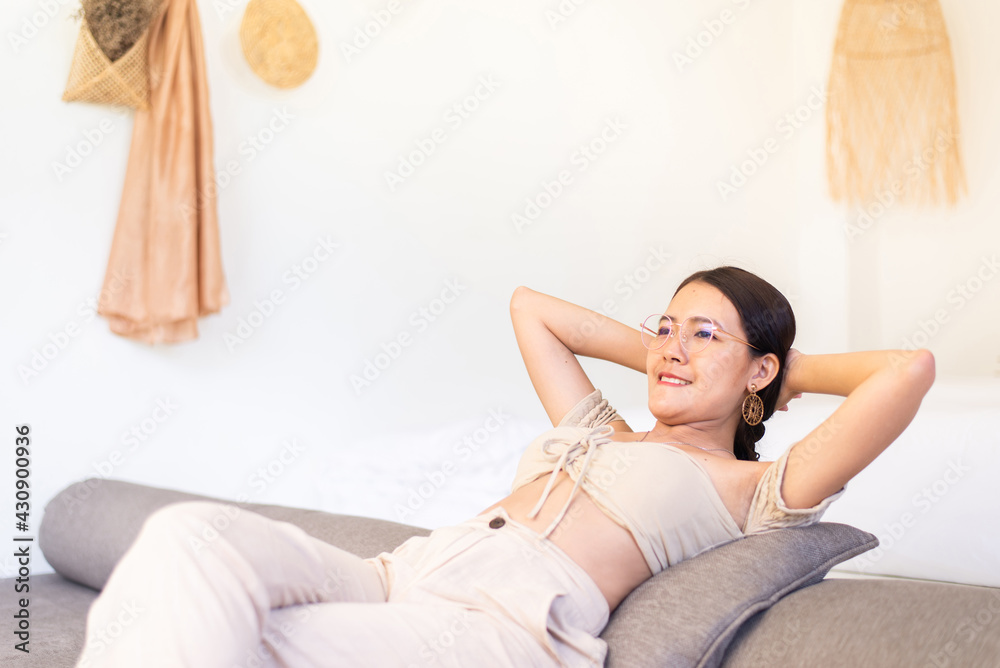 Happy woman looking on window while sitting on couch in living room with hands over head,Relax time