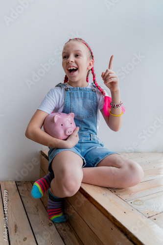 Teenage girl learns financial literacy. Child saving money in piggy bank. Vertical
