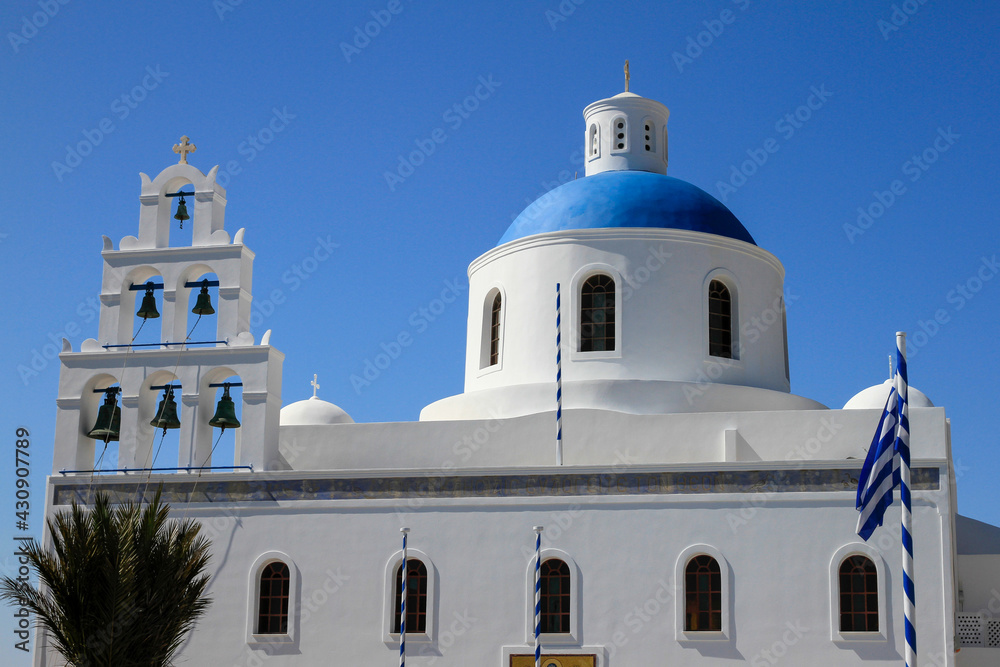 White Panagia Platsani Church with blue dome and bells against blue sky in Oia, Santorini, Greece