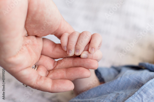 Close up of infant holding on to mother's finger