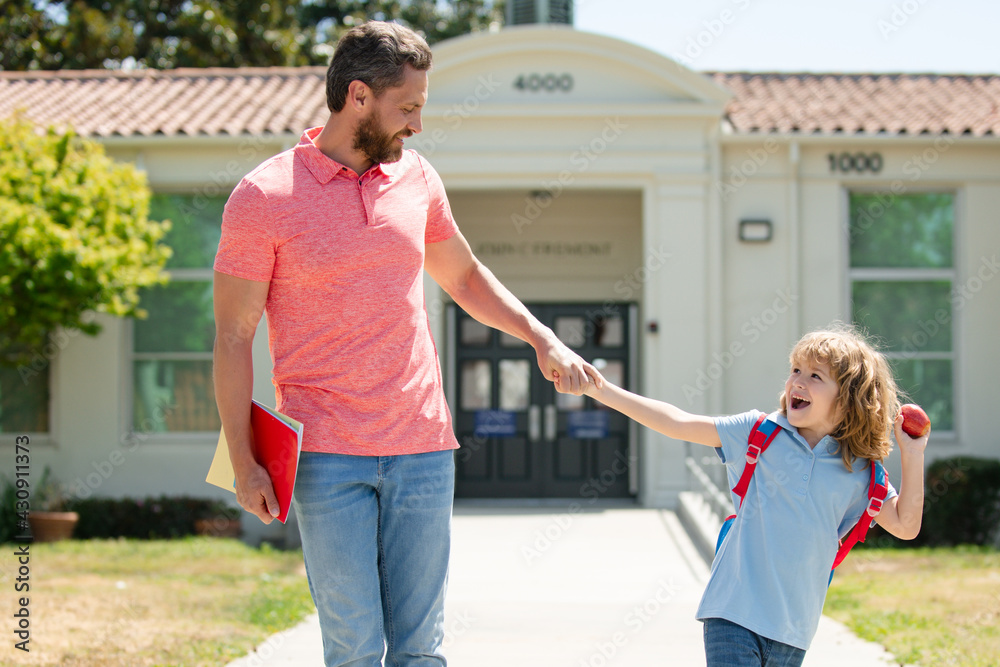 Obraz premium Father walking son to school. Parent and happy pupil of primary school schoolboy with backpack.