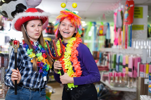 Two cheerful young female friends having fun in festival outfits store while preparing for party