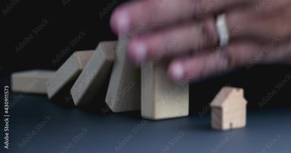 4K Video slow close up hand stop domino effect to make house icon fall . business concept of try to stop the domino effect in real estate industry.